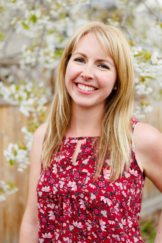 Photo of Naturopathic Doctor Erica Volk standing beside brick wall and smiling